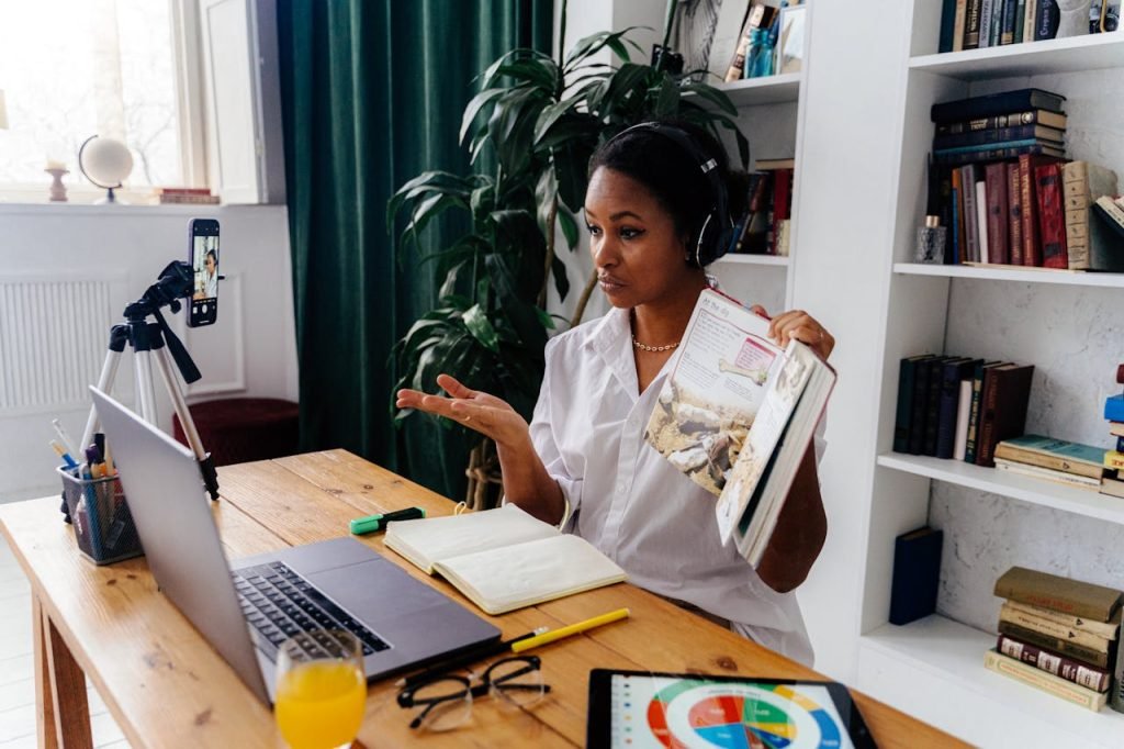woman-sitting-in-front-of-laptop-teaching-online-6266984 Woman conducting online teaching session at home with laptop and books.